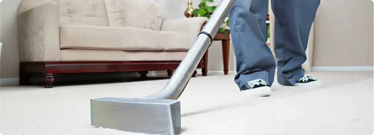 Carpet cleaning technician using a hot-water extraction wand on a light-colored carpet in a living room, Glendale, AZ.