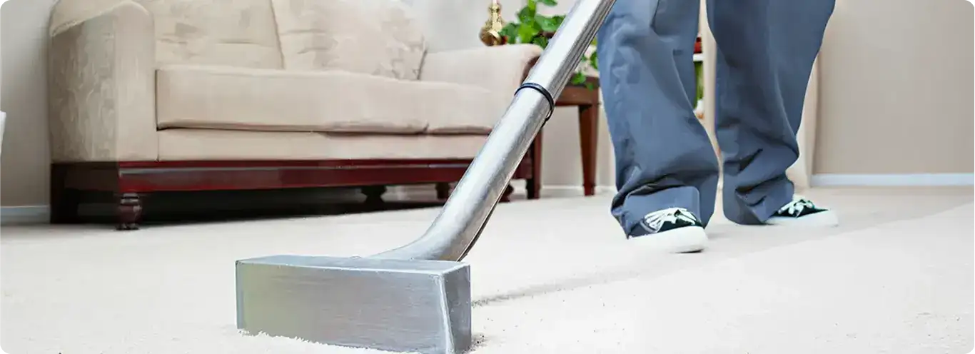 Carpet cleaning technician using a hot-water extraction wand on a light-colored carpet in a living room, Glendale, AZ.