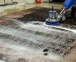 Professional rug cleaning with a rotary floor machine and shampoo foam, deep-cleaning an area rug, in Glendale, AZ.