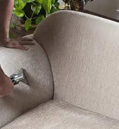 Professional upholstery cleaner deep-cleaning a fabric sofa with a handheld extraction tool and hose Glendale, AZ.